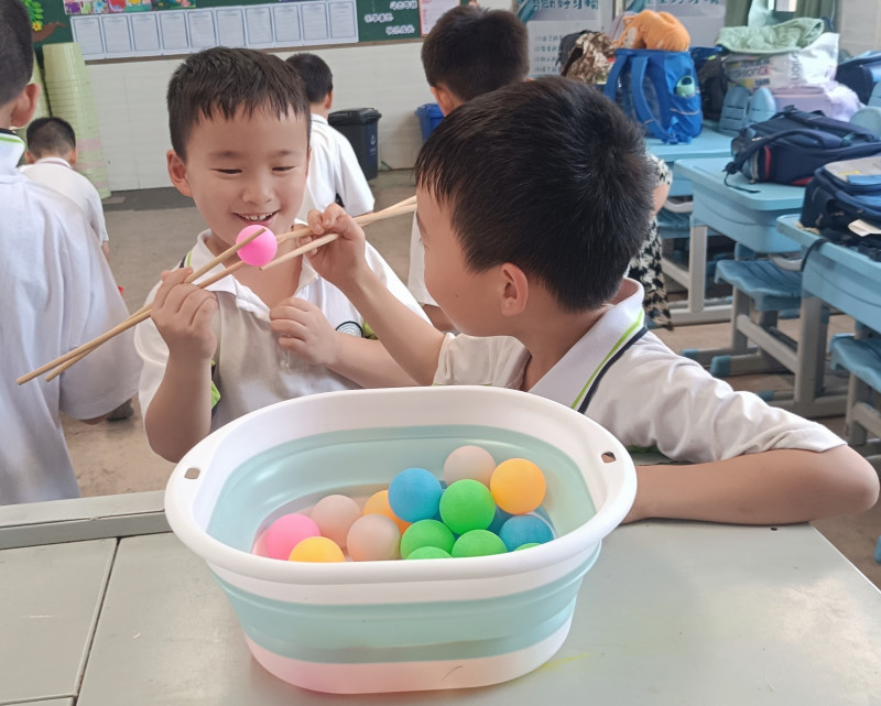 几名同学在玩“接力夹乒乓球”游戏。