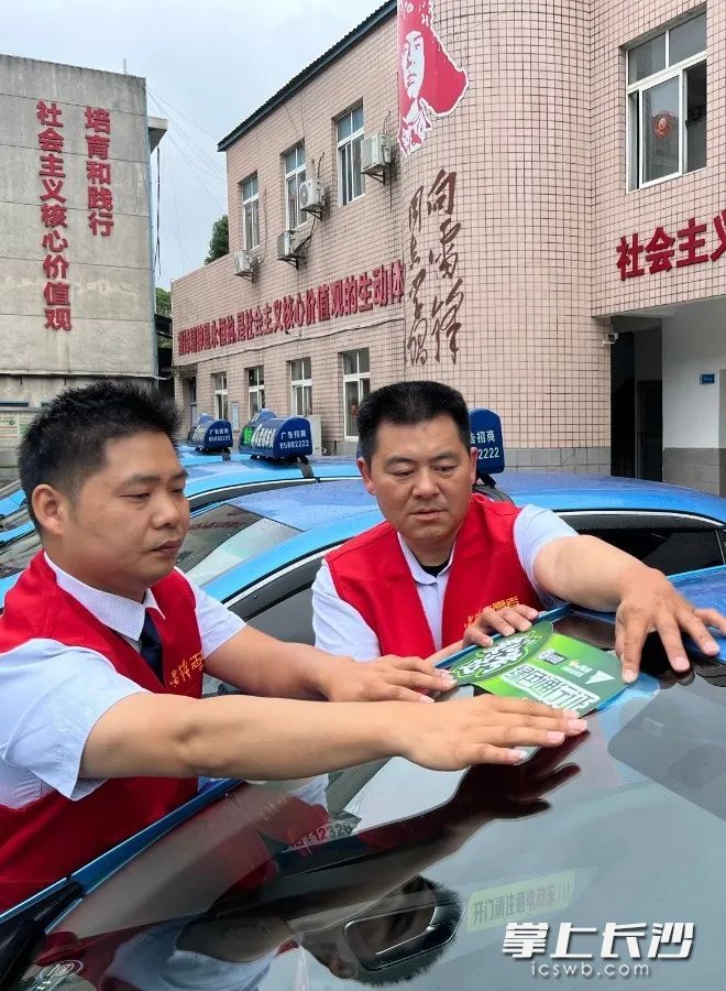 蓝的雷锋车队队员将“爱心送考绿色通行证”标识贴在出租车上。 长沙交投集团供图