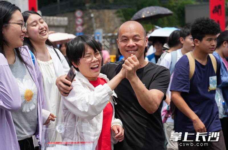 湖南师大附中考点，上午语文考试结束后，家长接到考生后握紧孩子的手加油鼓励。