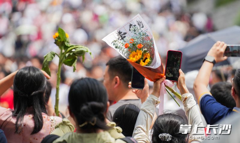 湖南师大附中考点外，家长高举向日葵等着孩子走出考场。