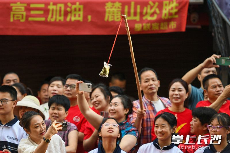 一位家长举着粽子为考生加油，寓意“一举高中”。