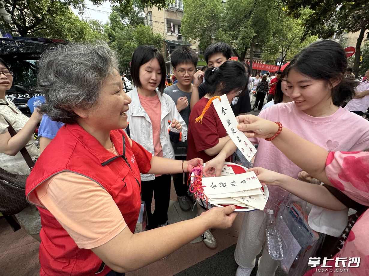 “长沙好人”高燕（左）拿着亲手写的祝福书签，在麓山国际实验学校考点外一一送给考生。  长沙晚报全媒体记者 林暘 摄
