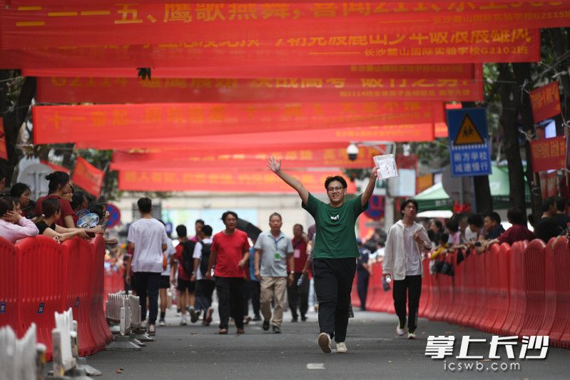 高考第一天的考试结束后，一位考生挥舞着双手跑出考场。