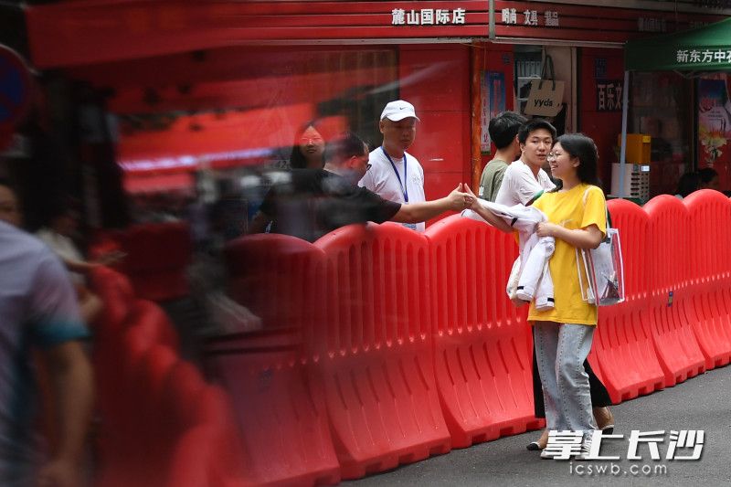 麓山国际实验学校外，一位家长隔着水马为孩子加油鼓劲。均为长沙晚报全媒体记者 郭雨滴 摄