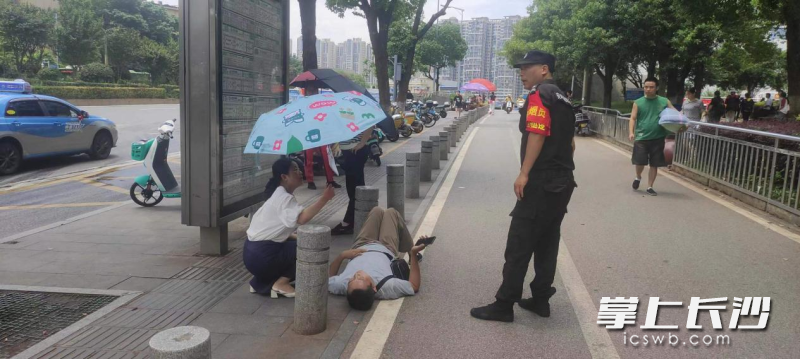 长沙市中心医院工作人员谈慧打着伞照顾着倒地老人，等待急救人员的到来。医院供图