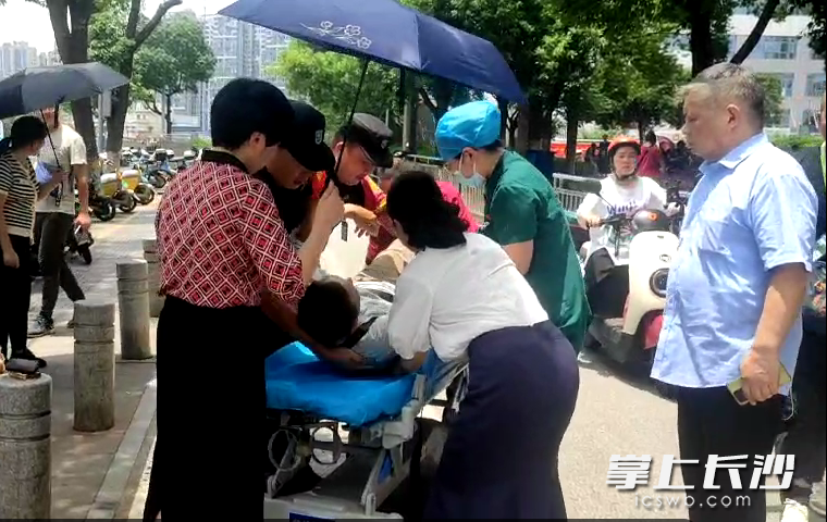 长沙市民和长沙市中心医院工作人员共同携手将倒地老人抬上担架。医院供图