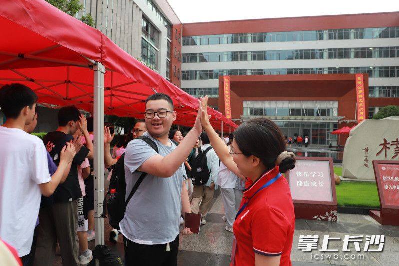 老师与学生击掌，祝福考试顺利。