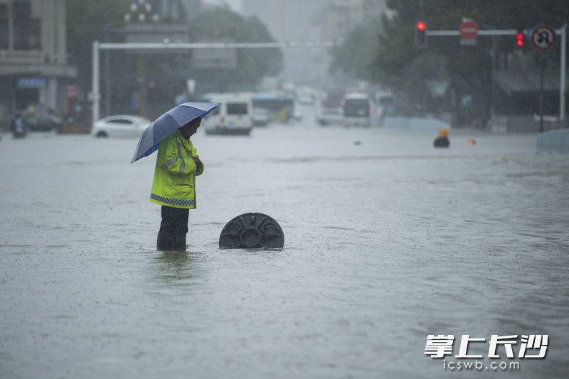 6月24日14时59分，芙蓉区车站中路，市政工作人员守着一处排水井，提醒着冒险涉水通行的车辆和行人。