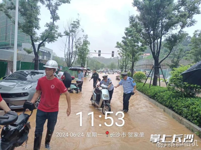 湘江新区行政执法局工作人员协助交巡警疏导交通，帮助行人和车辆脱困。