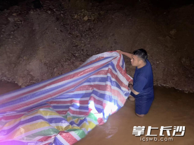 队员们与现场人员组成多条人力传输带，接力将沙袋装填到河堤上。