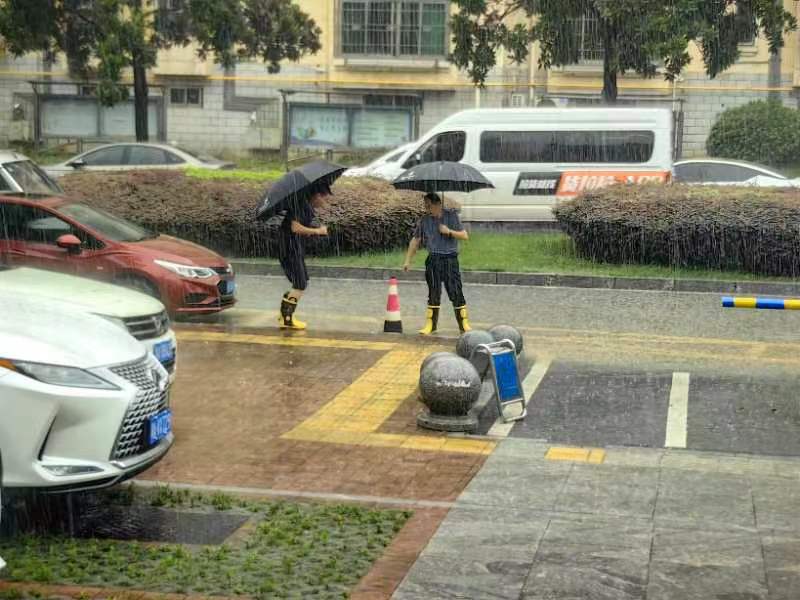 易长军带领社区工作人员现场查看情况，打开下水井盖泻流