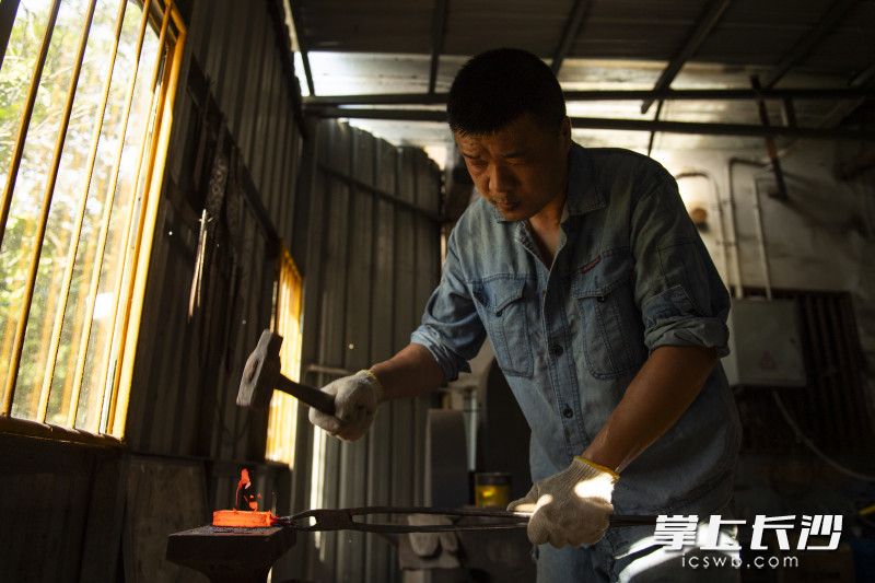 炉膛温度高达1200℃，炉光映红汗脸，他夹出刀胚再次锻打，铁屑火光溅起。