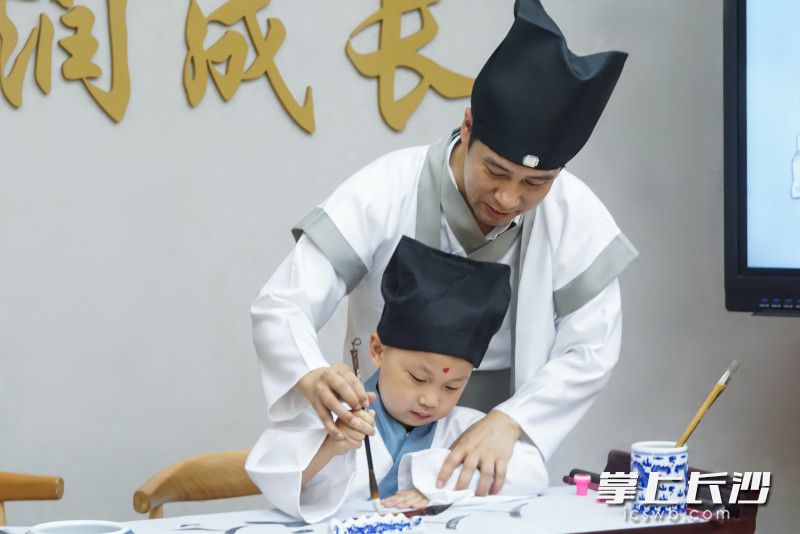 书院小学校长胡云华化身古代教书先生，带领一年级新生开笔写字，传承中华传统文化。学校供图