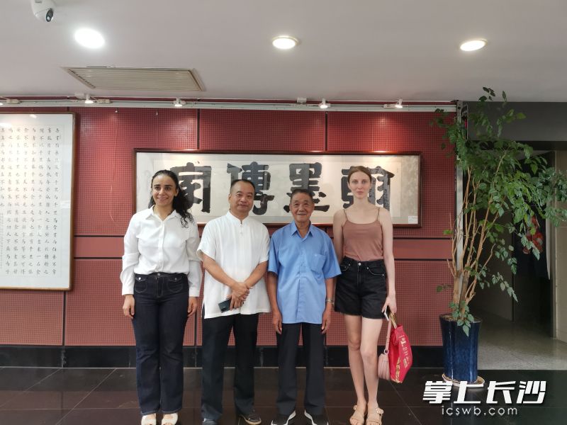 曹氏父子与外籍书法爱好者在《翰墨传家》作品前留影。  长沙晚报全媒体记者 梁瑞平 摄