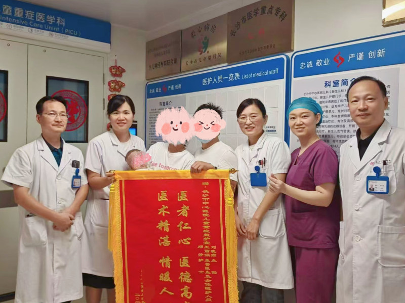 9月23日出院时，孩子的父母激动地将锦旗和感谢信送到医护人员手中并合影留念。医院供图