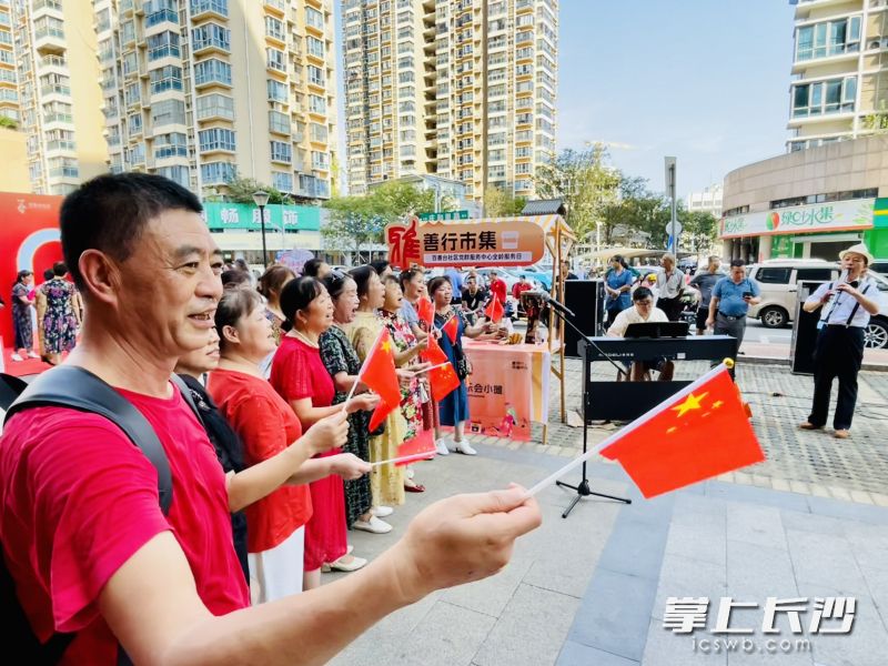 善行市集上，街头音乐人伴奏，居民们高唱《我和我的祖国》。