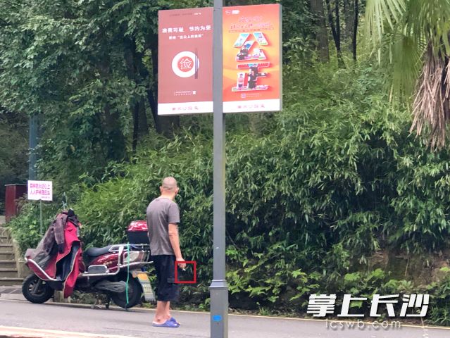 个别游客在公园林区附近抽烟，完全不顾旁边“森林防火记心上 人人护林理应当”的防火宣传标语。