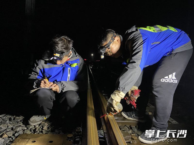 黄磊（右）和工友仔细检查道岔。