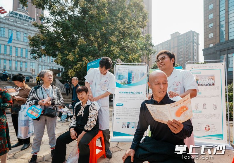 湖南省职业病防治院的医生为老人现场问诊、把脉。