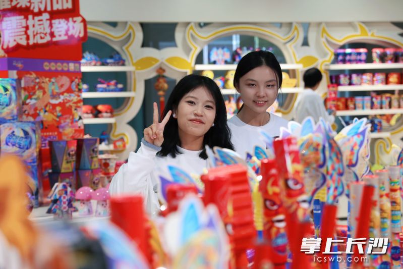 在庆泰花炮，两名女大学生站在琳琅满目的花炮产品中打卡合影。