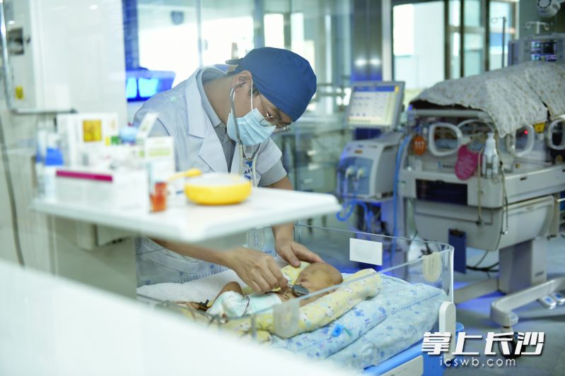 湖南省儿童医院新生儿科一病区副主任庄严查看安安的情况。