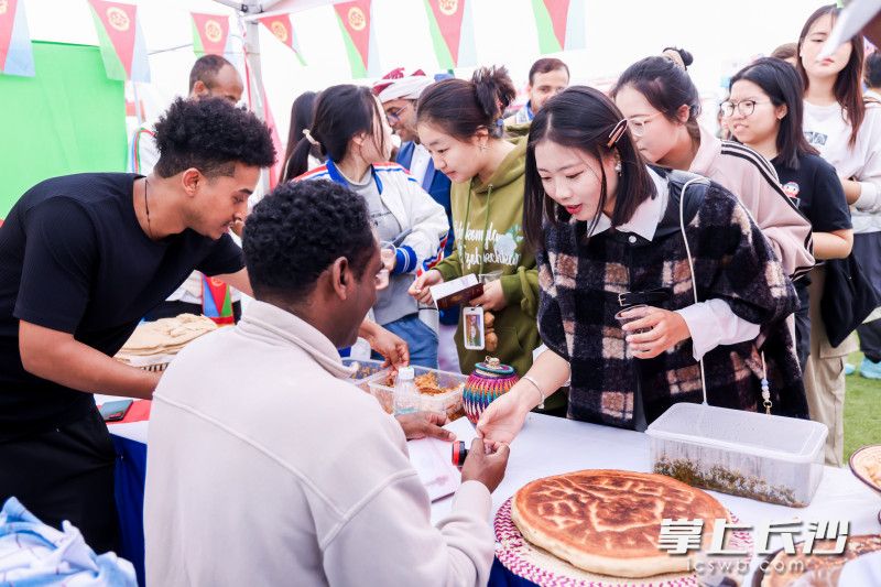 同学们在各国文化展位前品尝特色美食。