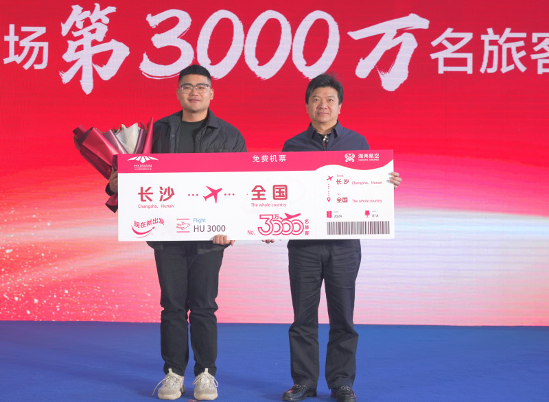湖南机场集团党委书记、董事长邱继兴为第3000万名幸运旅客芮海利颁发机票并送上鲜花。 长沙机场 供图