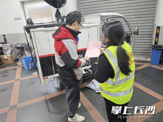 劝导员在快递营业网点发放宣传单，并提醒快递员重视交通安全。 均为长沙晚报通讯员李文供图
