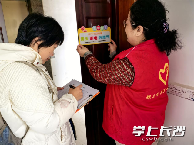 社区工作人员将温馨提示牌粘贴在住户门上。 均为长沙晚报通讯员 向玲娅 供图