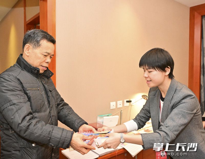 大会工作人员将证件、大会资料等交予前来报到的参会代表。