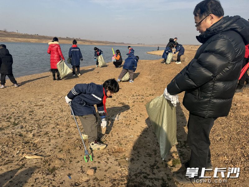 学生和家长们一起动手清洁河滩垃圾。
