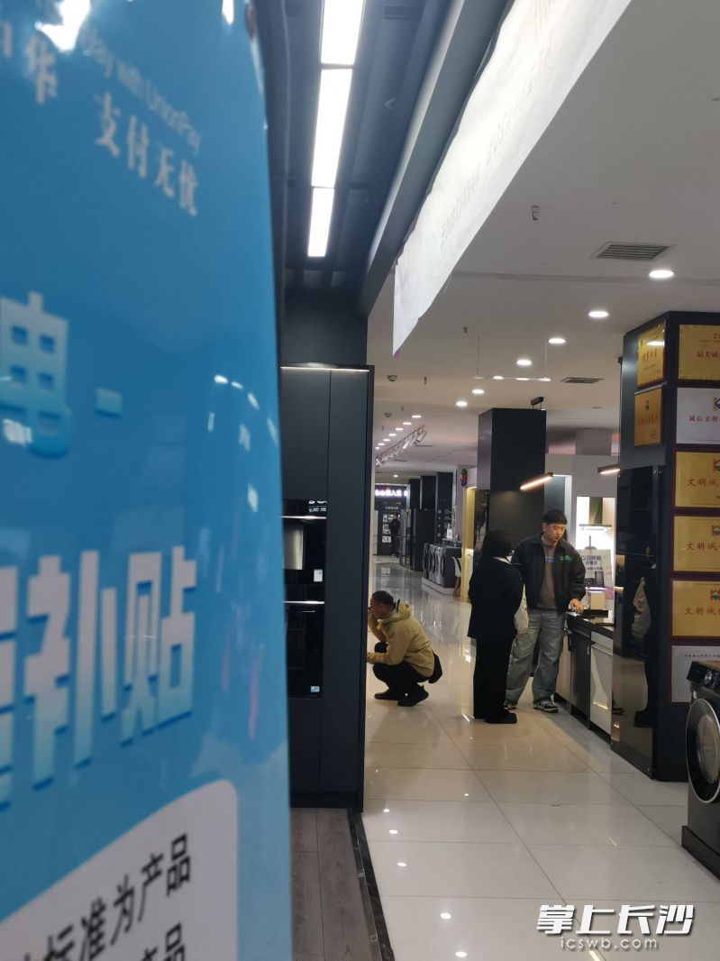 顾客正在细心挑选家电产品。