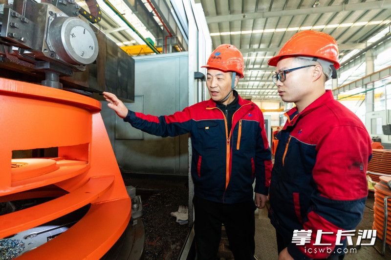 长利电气生产车间里，毛强（左）给技术工人介绍装配注意事项。 均为长沙晚报全媒体记者董阳摄