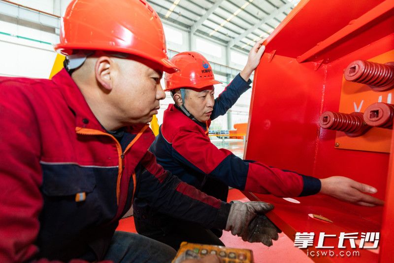 毛强仍在和技术工人们热烈探讨装配技巧。