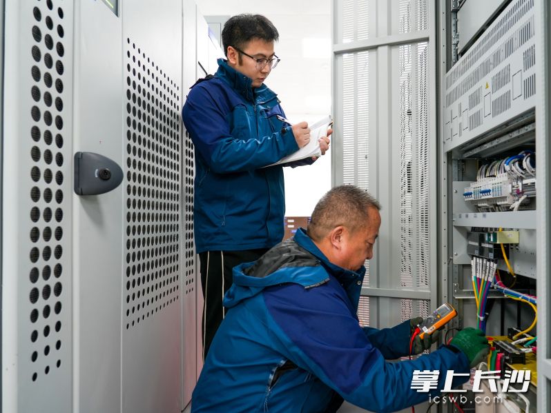 王建军和工友对电源屏进行检测。 均为全媒体记者 吴鑫矾 通讯员 阳云志 周伶莉 摄