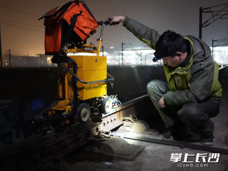 胡景蹲下检查钢轨探伤仪探头与钢轨耦合情况