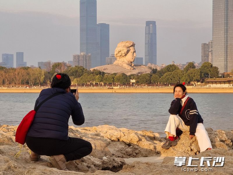 游人在江滩公园与青年毛泽东艺术雕塑合影。