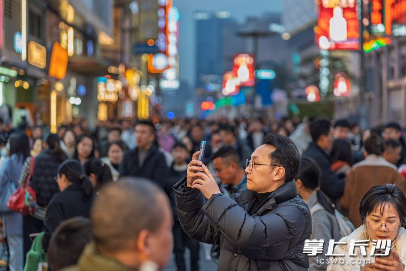 游客在人流中驻足拍照打卡。