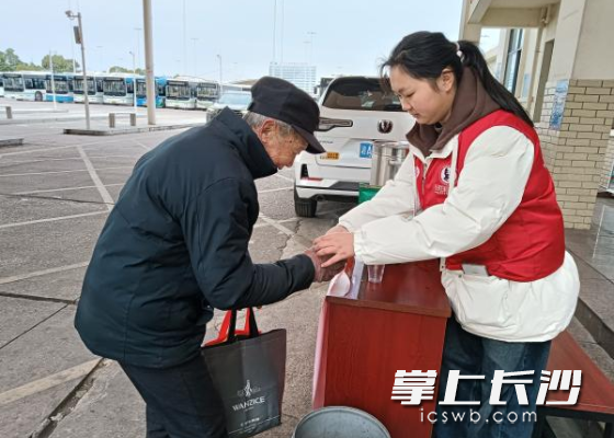 志愿者给一名旅客送上热茶。