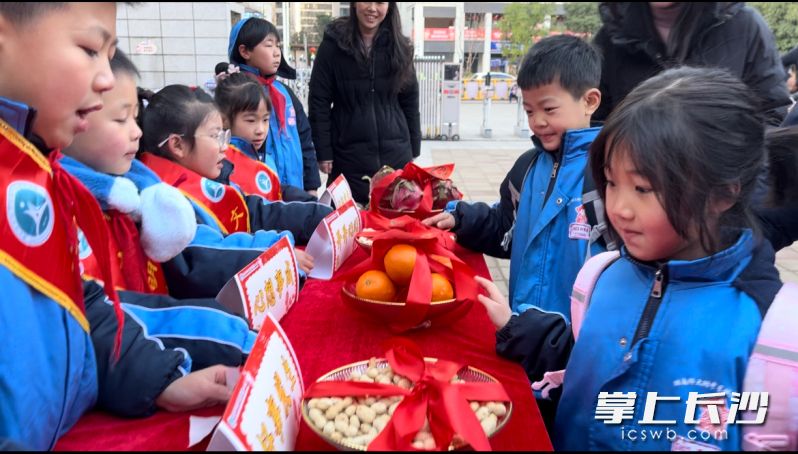 “福运长桌”上面摆着苹果、橘子、甘蔗、火龙果、花生等，“雷小锋”们轻轻触碰这些寓意祥瑞美好的物品。 均为长沙晚报通讯员郭智勇供图