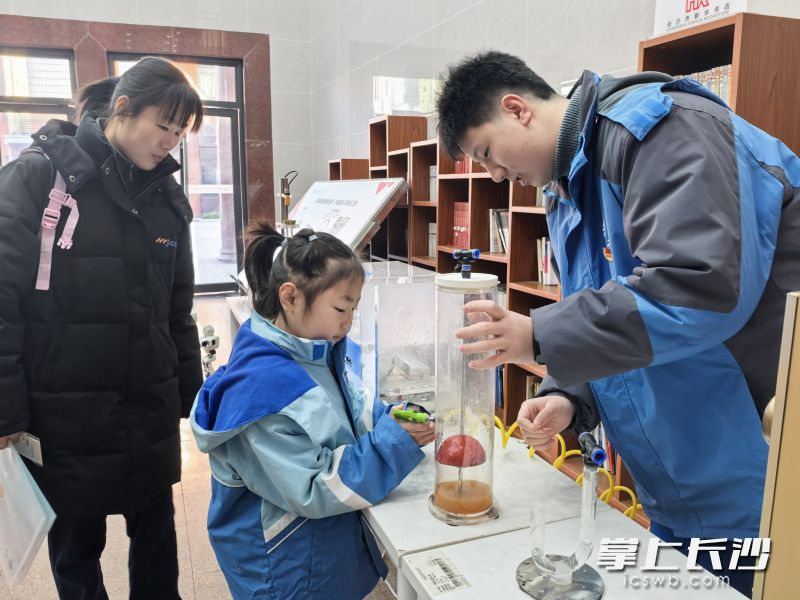一名小学生在大哥哥的指导下进行科技体验。