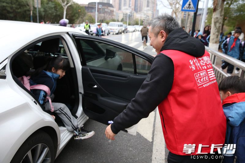 张家贵将孩子接下车，并一路牵着孩子的手将其护送进学校。