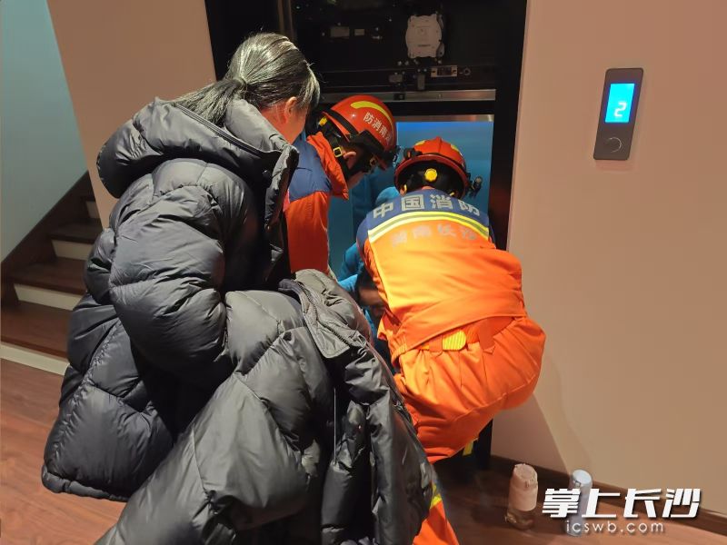 消防员协力帮助有身孕的王女士从故障电梯中出来。长沙晚报通讯员 彭宇环 摄