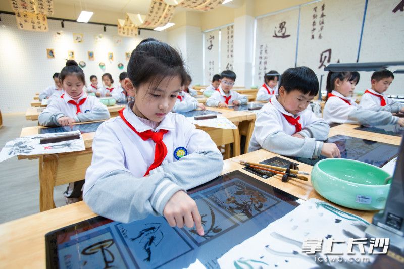 智慧书画教室里，学生借助智能临摹台进行国画创作。