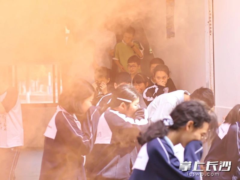 师生们弯腰捂鼻、护头前行。