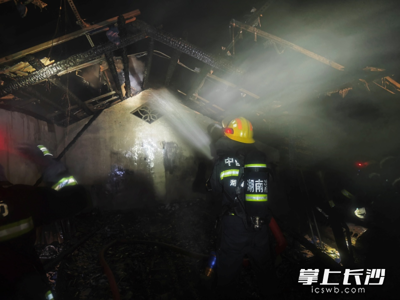 民房隔层起火，消防员奋力扑救。