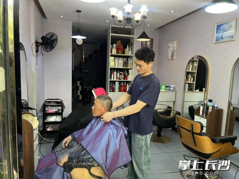 刘斌（右）正在给顾客理发。通讯员 彭穗 摄