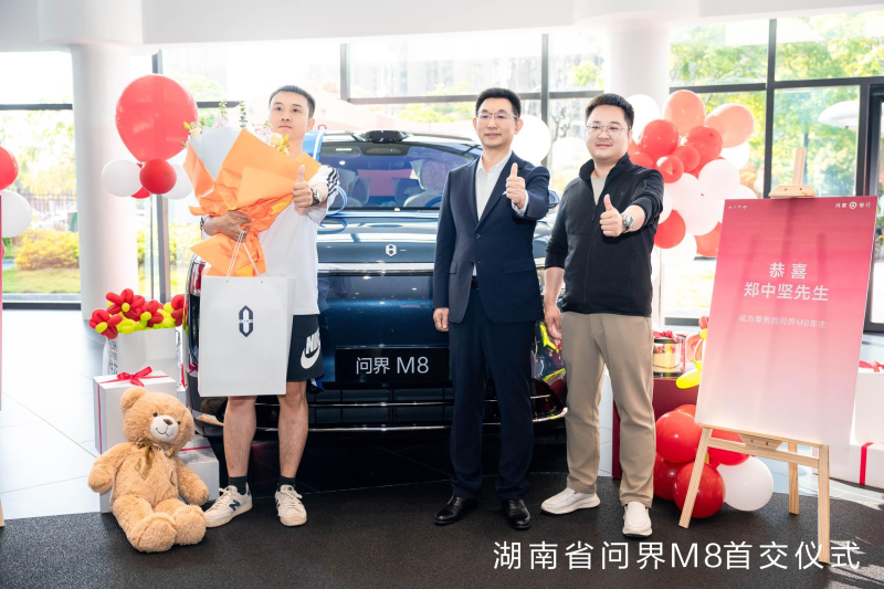 赛力斯汽车总裁何利扬（中）为问界M8车主送上鲜花和礼品。 均为鸿蒙智行供图