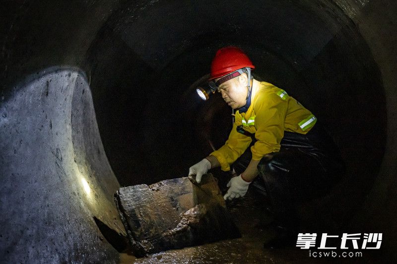 袁勤在检查过程中发现了一块有堵住管道风险的木板，随即将其打捞起来带出管道。