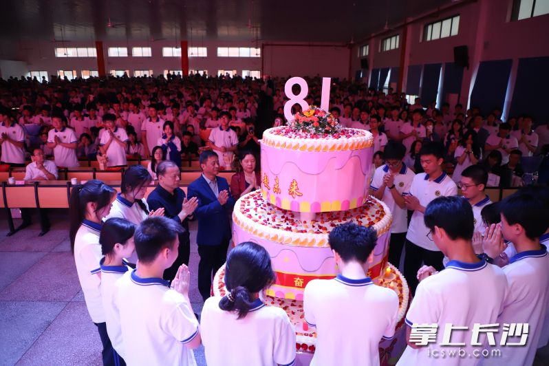 学生代表与学校领导、家长代表在18岁生日蛋糕前点上蜡烛，共同许下成人的第一个愿望。